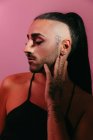 Visão lateral retrato de mulher barbuda transgênero glamourosa em sofisticado compõem posando com olhos fechados contra fundo rosa no estúdio — Fotografia de Stock