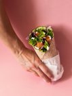 Zugeschnittene, unkenntlich gemachte Hände, die vegane Falafel-Packung auf buntem rosa Hintergrund halten — Stockfoto