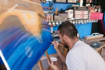 Uomo barbuto pittura puntini con pigmento bianco su tela con immagine astratta durante il lavoro in laboratorio creativo — Foto stock