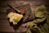 Vista dall'alto composizione di deliziosi fette di pane fatto in casa con erbe aromatiche e marmellata di frutta gialla dolce su tavolo di legno rustico — Foto stock