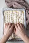Draufsicht einer gesichtslosen Person bei der Zubereitung von rohem Teig für Brot auf Backpapier auf dem Tisch — Stockfoto