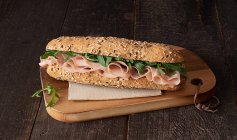 Von oben Mortadella-Sandwich mit Rucola auf dunklem Holztischhintergrund — Stockfoto