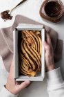 Top view of faceless female at table with raw dough prepared for Babka dessert and placed in metal baking dish — Stock Photo