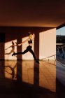 Junge athletische kaukasische Frau übt bei Sonnenuntergang Sprünge, Schatten und Licht im Hintergrund — Stockfoto