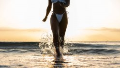 Mulher negra de colheita com tranças correndo na praia — Fotografia de Stock