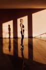 Joven atlética mujer caucásica haciendo ejercicio al atardecer, sombras y luz sobre el fondo - foto de stock
