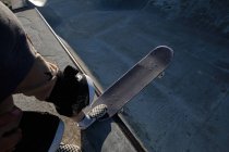 Зверху врожаю анонімний чоловічий ковзаняр стоїть зі скейтбордом на пандусі в скейт-парку — стокове фото