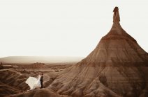 Alto angolo di sposo e sposa che si abbracciano vicino alla montagna contro il cielo nuvoloso al tramonto nel Parco Naturale di Bardenas Reales in Navarra, Spagna — Foto stock