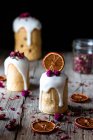 Vários deliciosos kulichs caseiros vertidos com esmalte doce e decorados com pedaços de laranja seca e flores na mesa de madeira — Fotografia de Stock