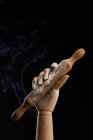 Роликовая шпилька в деревянной руке на черном фоне в студии, демонстрирующая концепцию кулинарного шоу — стоковое фото