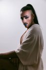 Портрет гламурной трансгендерной бородатой женщины в сложной сделать смотреть в камеру на нейтральном фоне — стоковое фото