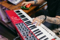 Cortar irreconhecível tatuado pianista masculino tocando sintetizador moderno ao compor música na mesa em estúdio de gravação — Fotografia de Stock