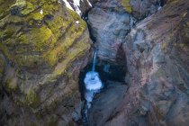 Von oben strömt sauberes Wasser, das von rauen, mit Moos bedeckten Felsen in der Landschaft Islands fällt — Stockfoto