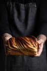 Homem de cultura irreconhecível em avental preto de pé com sobremesa de Babka de chocolate caseiro — Fotografia de Stock
