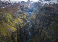 Dall'alto torrente di acqua pulita che cade da ruvide scogliere rocciose ricoperte di muschio nella campagna islandese — Foto stock