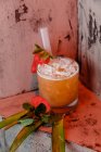Високий кут коктейлю Сан-Франциско, зроблений з горілки і апельсинового соку, прикрашеного полуницею і кубиками льоду, покладеними на пальмове листя. — стокове фото