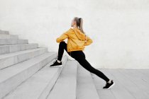 Молода атлетична біла жінка розтягується на відкритому повітрі біля сходів — стокове фото