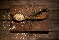 Composizione vista dall'alto con cucchiaio di legno riempito con fiocchi di farina d'avena sani posizionati sul tagliere su tavola rustica — Foto stock