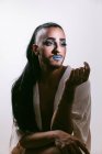 Porträt einer glamourösen Transgender-bärtigen Frau mit raffiniertem Make-up, die vor neutralem Hintergrund wegschaut — Stockfoto