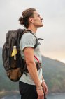 Seitenansicht eines männlichen Reisenden, der auf einem Felsen steht und beim Trekking im Sommer den Blick aufs Meer bewundert — Stockfoto