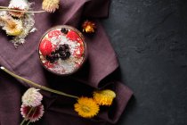 Вид зверху апетитна миска з полуницею і чорницею, розміщена на столі поблизу різних диких квітів — стокове фото