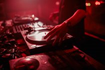 Vue latérale du DJ masculin mélangeant de la musique sur le contrôleur pendant le concert dans une boîte de nuit sombre — Photo de stock