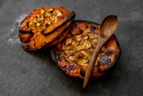 Dall'alto di metà di zucca al forno sane appetitose saporite con semi su tavolo grigio — Foto stock