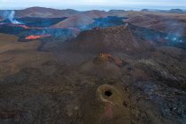 Drone vista del arroyo de lava naranja caliente que fluye a través del terreno montañoso en la mañana en Islandia - foto de stock