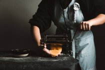 Persona irriconoscibile che prepara ravioli e pasta a casa. Sta usando una macchina per la pasta — Foto stock