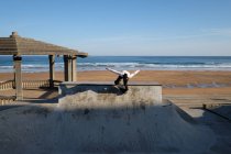 Невпізнаваний підліток-хлопчик катається на скейтборді в скейт-парку в сонячний день на березі моря — стокове фото