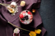 Вид зверху апетитна миска з полуницею і чорницею, розміщена на столі поблизу різних диких квітів — стокове фото