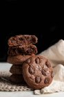 Pilha de biscoitos de centeio de chocolate colocados na placa de vime perto de guardanapo no fundo branco — Fotografia de Stock