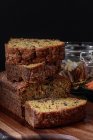 Carrot cake cut into pieces stacked on a wood next to a jar full of walnuts — Stock Photo