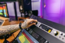 Неузнаваемый татуированный звукорежиссёр, работающий с пультом управления на аудиоплате в студии звукозаписи — стоковое фото