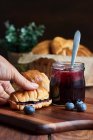 Zubereitung eines Frühstücks mit Croissants und Blaubeermarmelade auf einem Holztisch — Stockfoto
