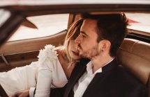 Высокий угол женщины, лежащей на плече мужчины, сидя внутри автомобиля в день свадьбы — стоковое фото