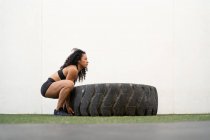 Side view of muscular Asian female athlete flipping heavy tire during intense training — Stock Photo