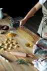 Pessoa irreconhecível preparando raviolis e massas em casa. Ela está derramando farinha na massa — Fotografia de Stock