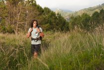 Male backpacker standing in meadow at sundown during trekking in summer and looking away — Stock Photo