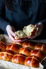 Жіночий пекар відкриває пух свіжоспечений гарячий хрест булочки на випічці лоток — стокове фото