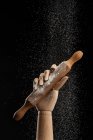 Rolling pin in flour in wooden hand on black background in studio showing concept of culinary — Stock Photo