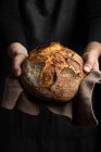 Chef de culture méconnaissable dans tablier debout avec morceau de pain fraîchement cuit — Photo de stock