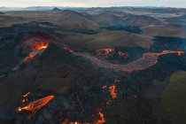 Drone vista do córrego de lava laranja quente que flui através de terreno montanhoso de manhã na Islândia — Fotografia de Stock