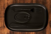 Vista dall'alto di forchetta nera e coltello posizionati vicino a conserve sigillate su vassoio nero rettangolare — Foto stock