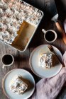 Вище трьох молочних торт у випічці та тарілках з чашками міцної кави на дерев'яному столі — стокове фото