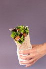 Zugeschnittene, unkenntlich gemachte Hände, die vegane Falafel-Packung auf lila Hintergrund halten — Stockfoto