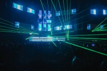 Яскраво-зелені неонові промені освітлюють сучасний темний концертний зал під час живого музичного виступу — стокове фото