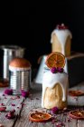 Varios deliciosos kulichs caseros vertidos con glaseado dulce y decorados con trozos de naranja seca y flores en la mesa de madera - foto de stock