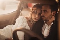 Высокий угол женщины, лежащей на плече мужчины, сидя внутри автомобиля в день свадьбы — стоковое фото