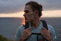 Männlicher Reisender steht auf einem Felsen und bewundert die Aussicht auf das Meer beim Trekking im Sommer — Stockfoto